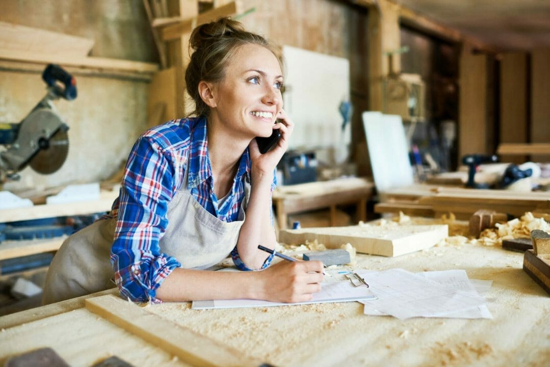 Portrait Of Cheerful Female Carpenter Talking On Smartphone.