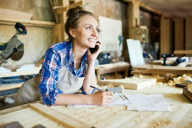 Portrait Of Cheerful Female Carpenter Talking On Smartphone.