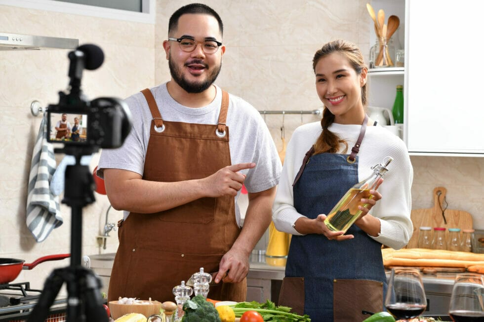 Male chef recording video content with female influencer as guest.