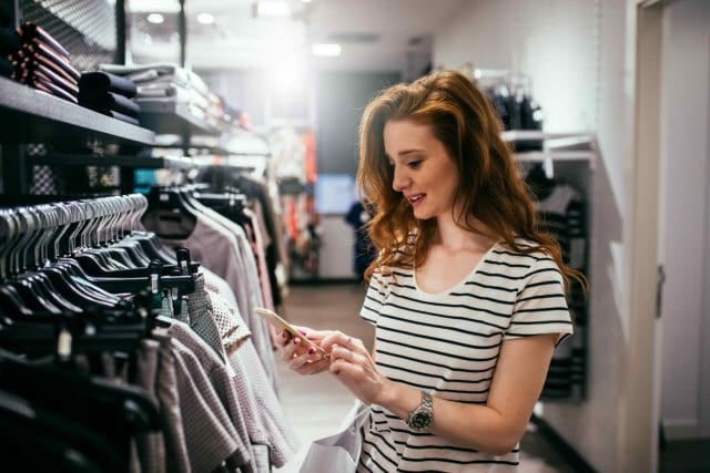 Female consumer browses social media while shopping.