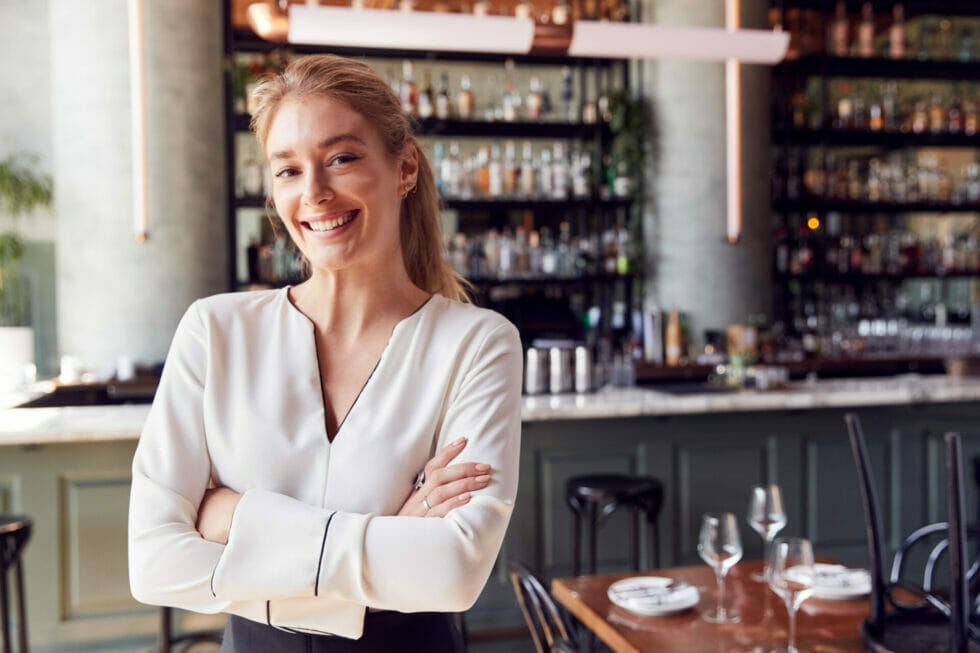 Young franchised restaurant owner standing by the bar counter.