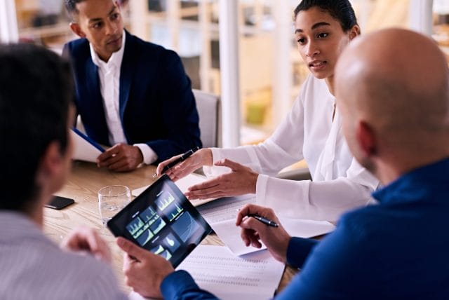 Upper management Meeting In A Conference Room To Evaluate Data On Tablets